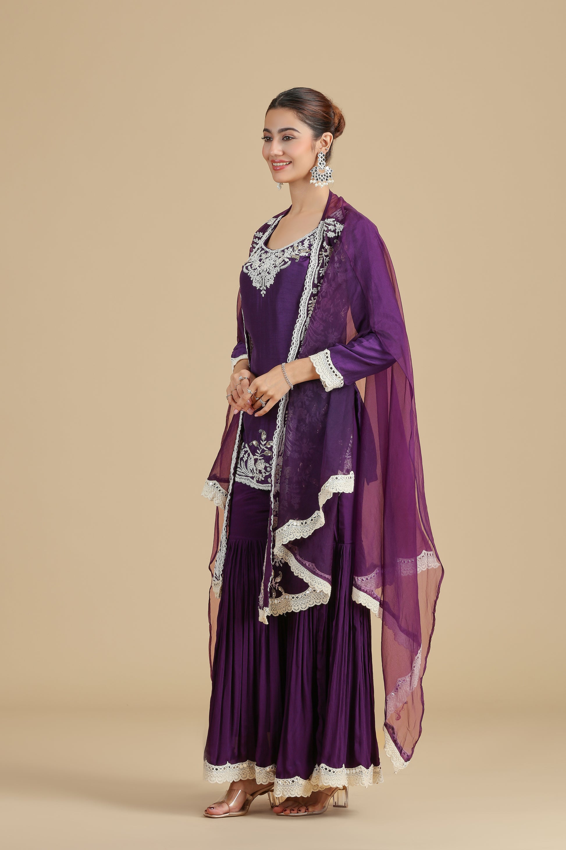 Woman wearing a purple kurta set outfit with white patterns on a beige background