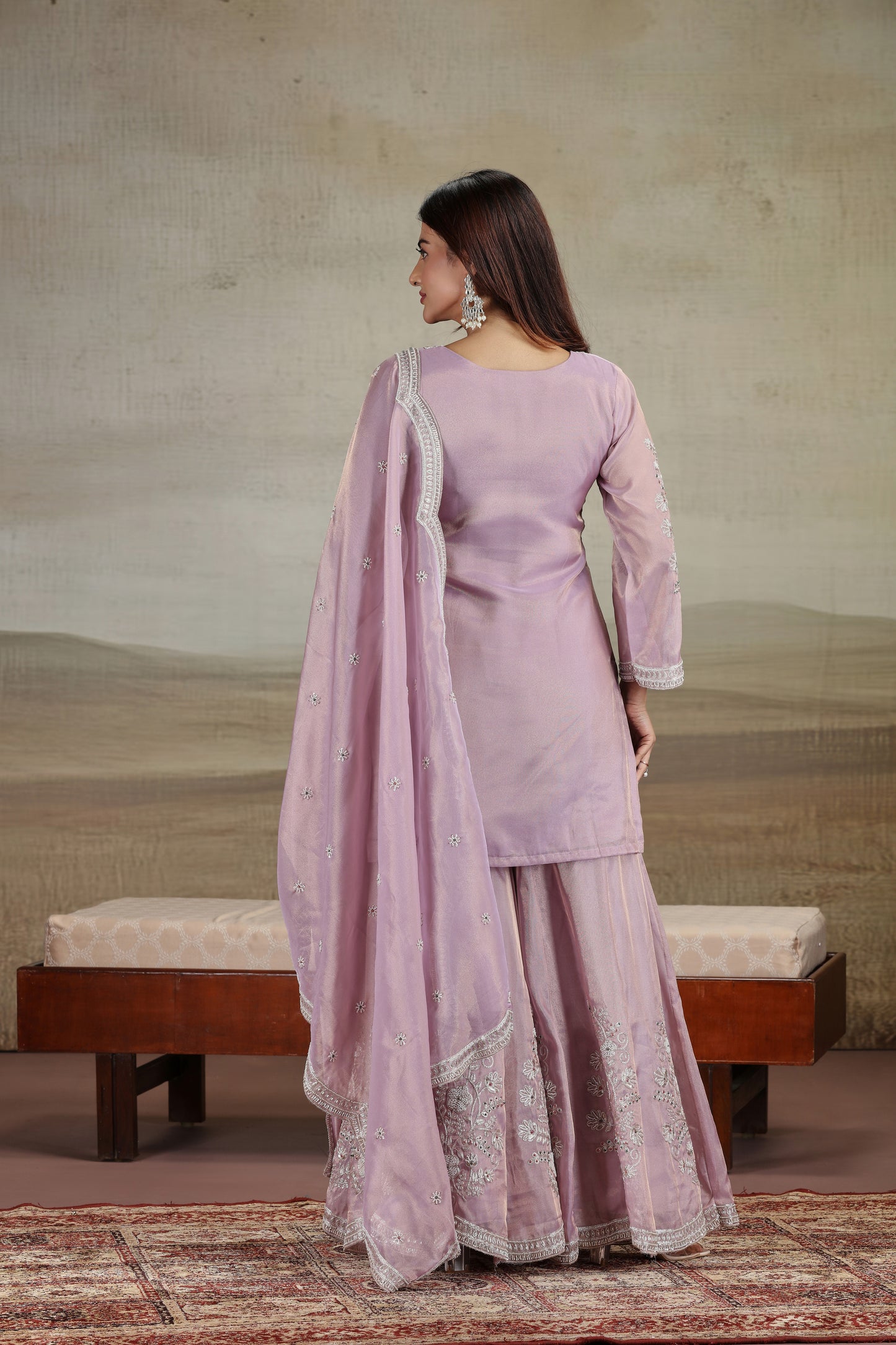 Woman in a lavender traditional outfit with a matching dupatta, standing against a neutral background.