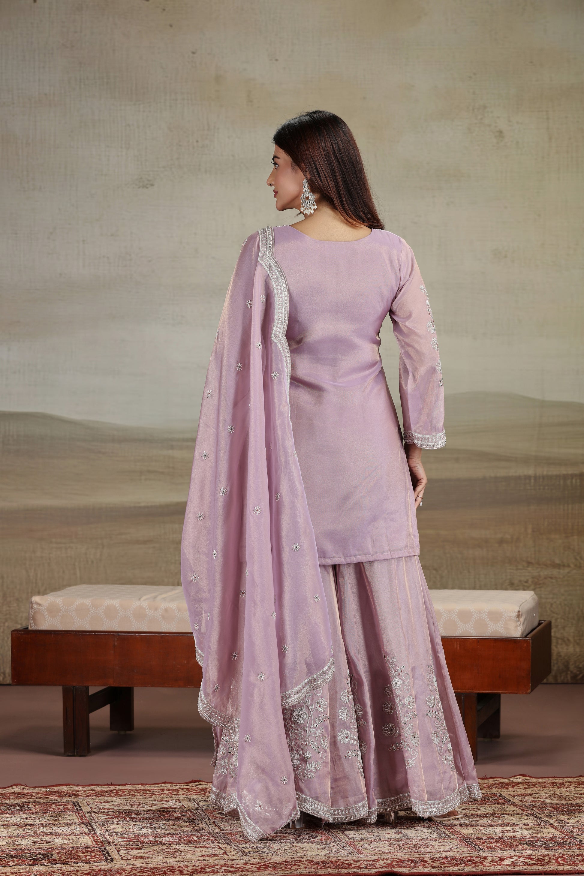 Woman in a lavender traditional outfit with a matching dupatta, standing against a neutral background.